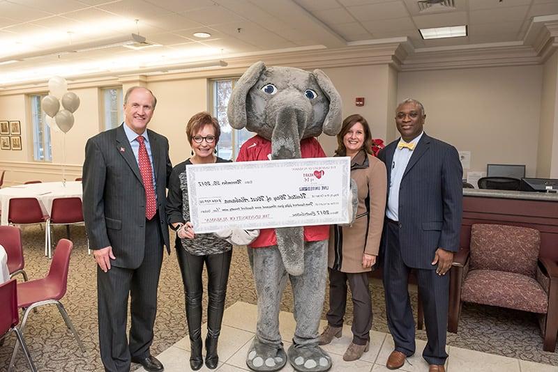 Big Al, University leadership, and United Way leadership members hold a giant check